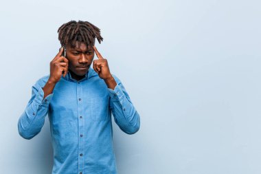 Genç rasta siyah adam parmak ile tapınağını işaret eden bir telefon tutan, düşünme, bir görev üzerinde duruldu.