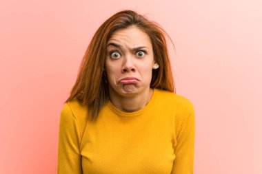 Genç güzel genç kadın omuz silkiyor ve açık gözleri karışık.