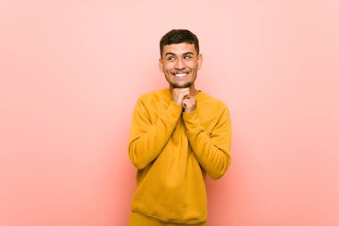 Genç İspanyol adam çene altında ellerini tutar, mutlu bir kenara bakıyor.