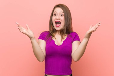 Bir zafer ya da başarı kutlayan pembe bir duvara karşı genç İspanyol kadın, o şaşırır ve şok.