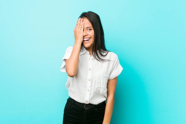 Mavi bir duvara karşı Genç İspanyol serin kadın palmiye ile yüz yarısını kapsayan eğlenceli.