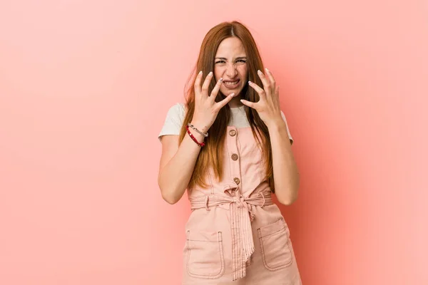 Young ginger woman with freckles upset screaming with tense hands.