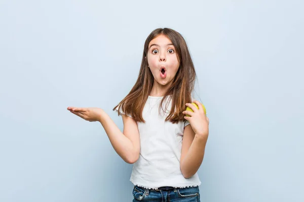 Pequeña Chica Caucásica Sosteniendo Una Manzana Verde Impresionada Sosteniendo Espacio — Foto de Stock