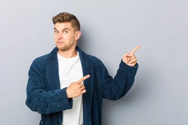 Joven Hombre Caucásico Usando Pijama Impactado Señalando Con Los Dedos —  Fotos de Stock