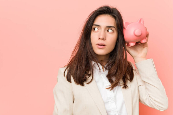 Молодая белая женщина держит копилку

