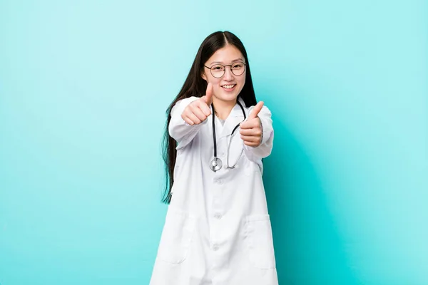 Young chinese doctor woman with thumbs ups, cheers about something, support and respect concept.