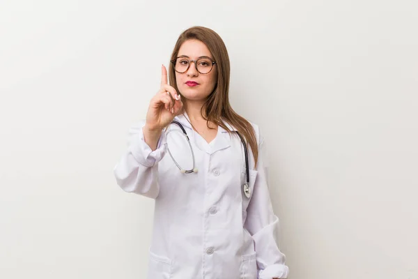 Jonge Dokter Vrouw Tegen Een Witte Muur Met Nummer Een — Stockfoto