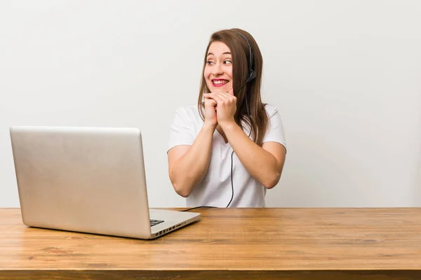 Jovem Mulher Telemarketer Mantém Mãos Debaixo Queixo Está Olhando Alegremente — Fotografia de Stock