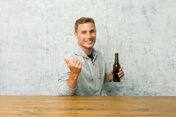 Jovem Bebendo Uma Cerveja Uma Mesa Pontos Com Dedo Polegar — Fotografia de Stock