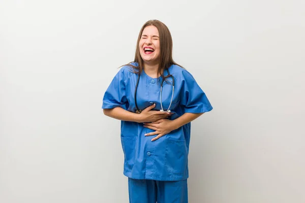 Jonge Verpleegster Vrouw Tegen Een Witte Muur Lacht Gelukkig Heeft — Stockfoto