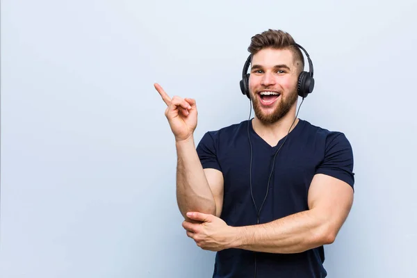 Unga Kaukasiska Man Lyssnar Musik Leende Glatt Pekar Med Pekfingret — Stockfoto