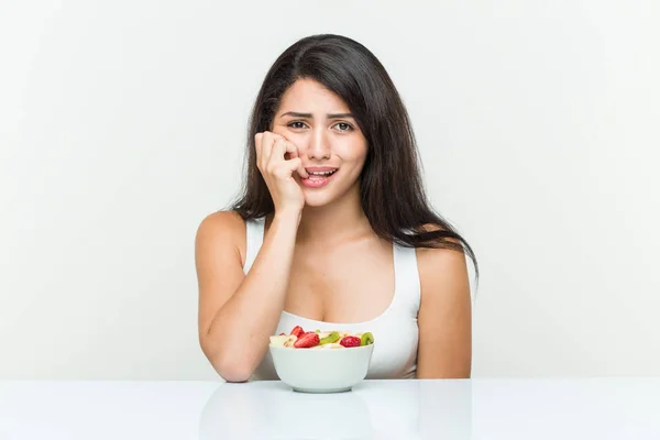 Giovane Donna Ispanica Mangiare Una Ciotola Frutta Mordere Unghie Nervoso — Foto Stock