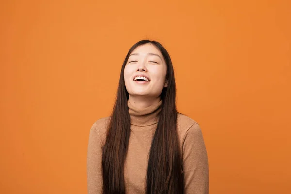 Young pretty chinese woman relaxed and happy laughing, neck stretched showing teeth.