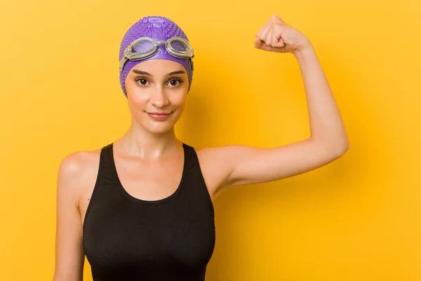 Young caucasian swimmer woman against a yellow background