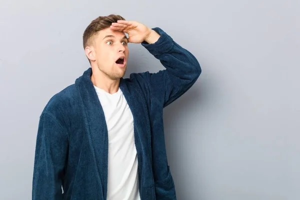 Joven Hombre Caucásico Usando Pijama Mirando Lejos Manteniendo Mano Frente —  Fotos de Stock