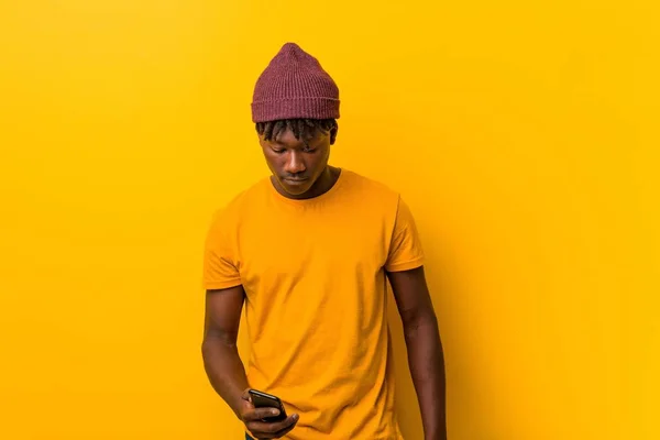 Молодой Африканский Человек Стоящий Жёлтом Фоне Шляпе Телефоном — стоковое фото
