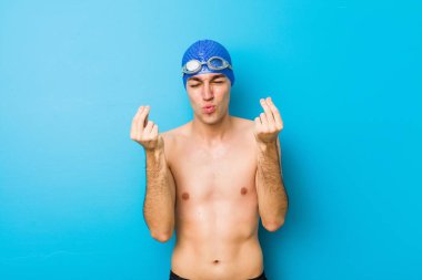 Parası olmadığını gösteren genç yüzücü adam.