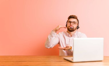 Bir çağrı merkezinde çalışan genç adam iki eliyle bir şey tutarak, ürün sunumu.