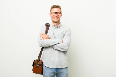 Kafkasyalı genç bir iş adamı, kararlı bir şekilde kollarını kavuşturuyor..