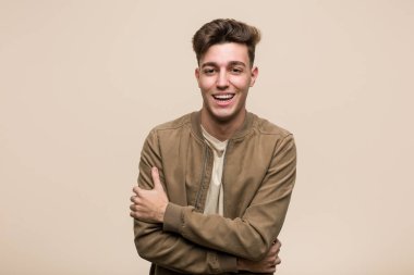 Kahverengi bir ceket giyen genç beyaz adam gülüyor ve eğleniyor.