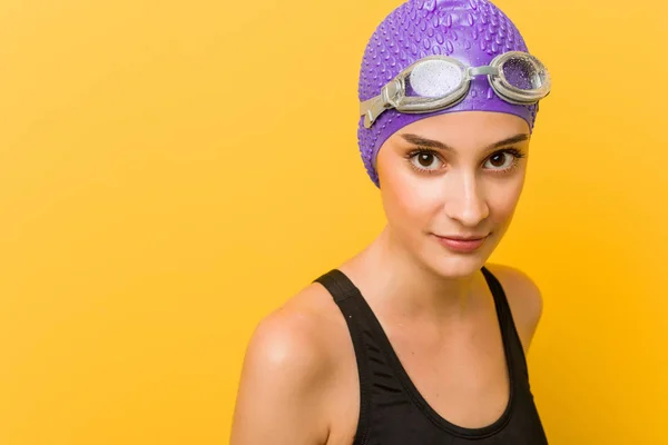 Young caucasian swimmer woman against a yellow background