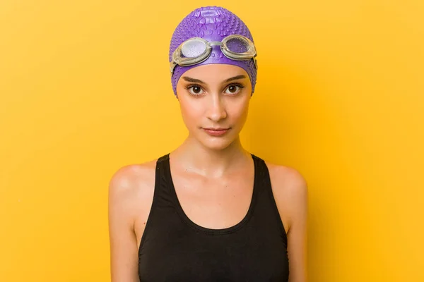 Young caucasian swimmer woman against a yellow background