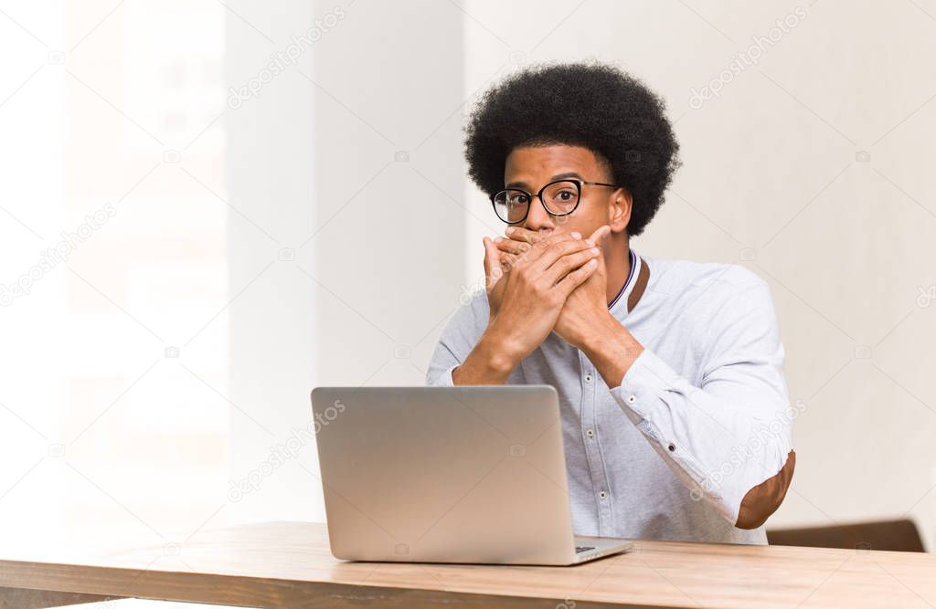 Young black man using his laptop surprised and shocked