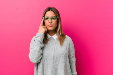 Genç otantik karizmatik gerçek insanlar kadın parmak ile tapınak işaret bir duvara karşı, düşünme, bir görev üzerinde duruldu.