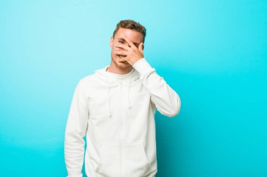 Genç kafkas spor adam parmakları ile kameraya göz kırpma, utanç yüzü kapsayan.