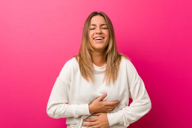 Bir duvara karşı Genç otantik karizmatik gerçek insanlar kadın mutlu güler ve mide ellerini tutmak eğlenceli.