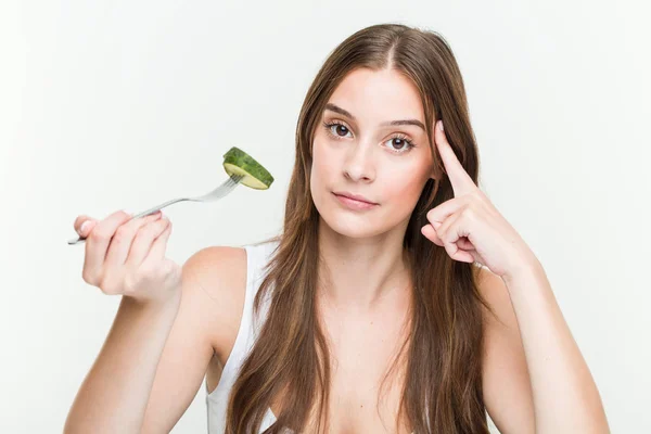 Joven Mujer Caucásica Comiendo Pepino Señalando Sien Con Dedo Pensando —  Fotos de Stock