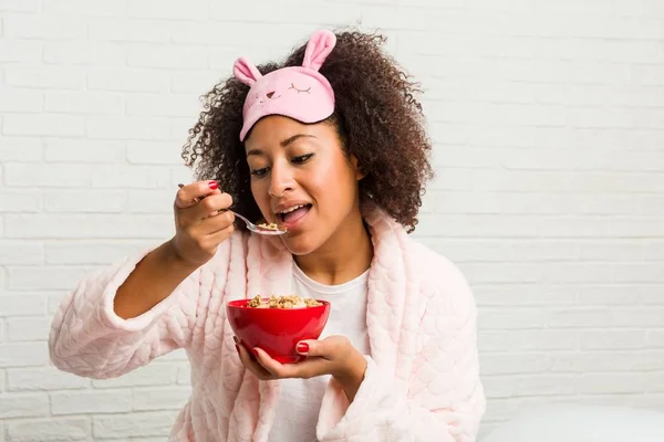 Young african american woman eating a cereal bowl on the bed