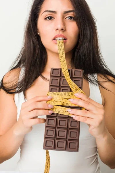 Giovane Donna Ispanica Possesso Una Tavoletta Cioccolato Pensando Alla Dieta — Foto Stock