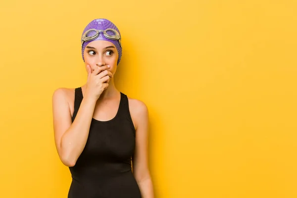 Young swimmer caucasian woman thoughtful looking to a copy space covering mouth with hand.