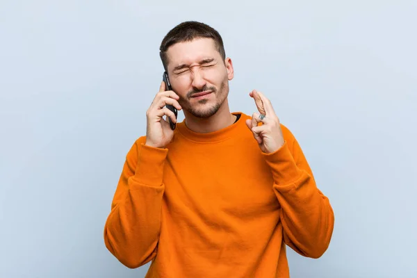 Giovane Uomo Caucasico Possesso Telefono Incrociando Dita Avere Fortuna — Foto Stock