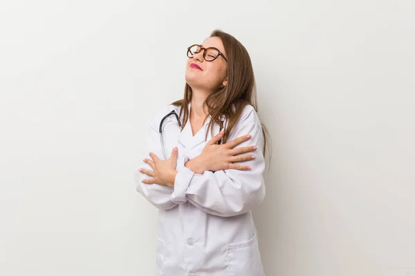 白い壁に対する若い医師の女性は 気楽に笑顔と幸せにハグ — ストック写真
