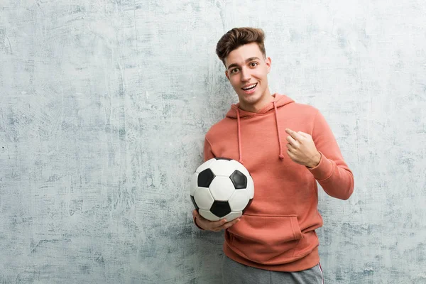 Joven Deportista Sosteniendo Una Pelota Fútbol Sorprendido Señalándose Mismo Sonriendo —  Fotos de Stock