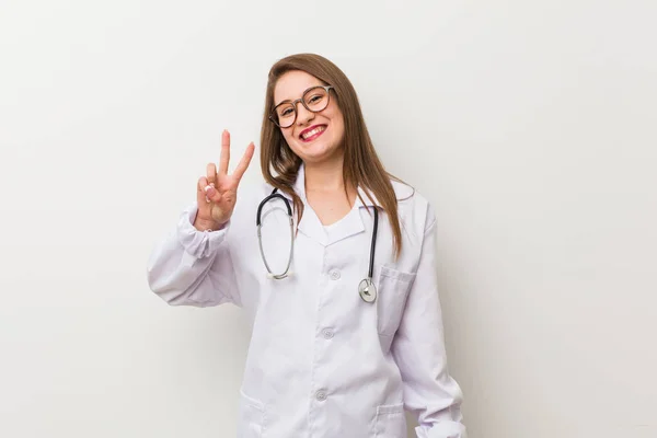 Jonge Dokter Vrouw Tegen Een Witte Muur Tonen Overwinning Teken — Stockfoto