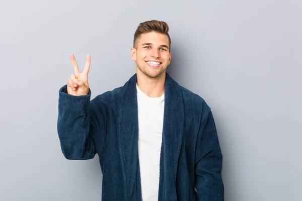 Joven Hombre Caucásico Usando Pijama Mostrando Signo Victoria Sonriendo Ampliamente —  Fotos de Stock