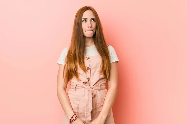 Young ginger woman with freckles confused, feels doubtful and unsure.