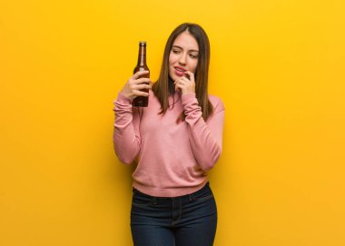 Bir bira tutan genç sevimli kadın bir kopya alanı bakarak bir şey hakkında düşünme rahat