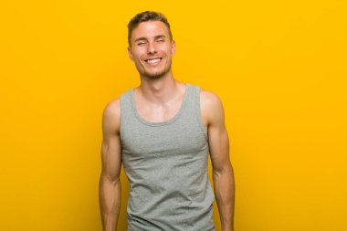 Genç kafkas spor adam güler ve gözleri kapatır, rahat ve mutlu hissediyor.