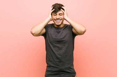 Genç İspanyol rahat adam sevinçle baş ellerini tutarak gülüyor. Mutluluk kavramı.