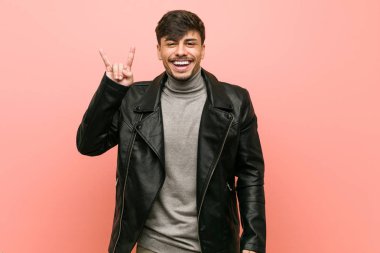 Bir devrim konsepti olarak boynuzları jest gösteren bir deri ceket giyen genç İspanyol adam.