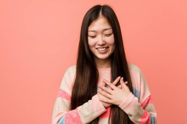 Genç serin Çinli kadın kalp, mutluluk kavramı ellerini tutarak gülüyor.