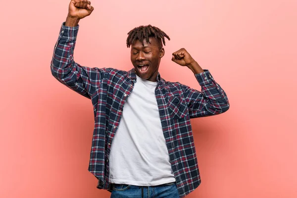 Young african black man celebrating a special day, jumps and raising arms with energy.