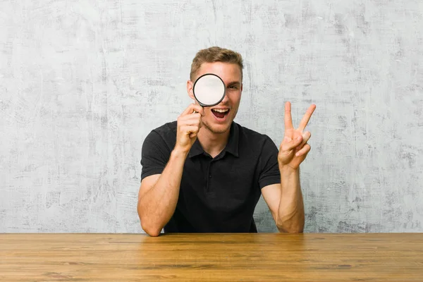 Joven Hombre Guapo Sosteniendo Una Lupa Mostrando Signo Victoria Sonriendo — Foto de Stock