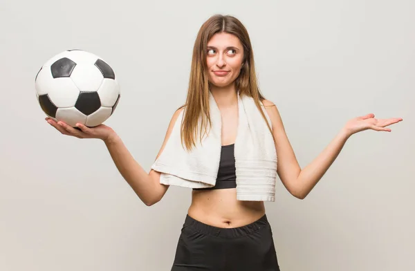 若いフィットネスロシアの女性は混乱し 疑わしい サッカーボールを持つ — ストック写真
