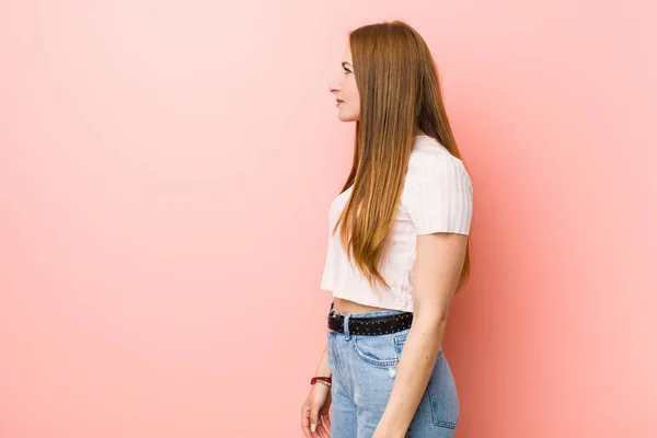 Jonge Roodharige Gember Vrouw Tegen Een Roze Muur Staren Links — Stockfoto