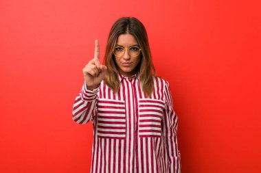 Genç otantik karizmatik gerçek insanlar kadın parmak ile bir numara gösteren bir duvara karşı.